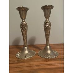 two silver candlesticks sitting on top of a wooden table