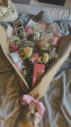 a bouquet of flowers on a bed with a phone in the middle and some books