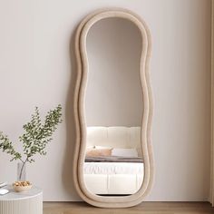 an oval shaped mirror sitting on top of a wooden floor next to a white table