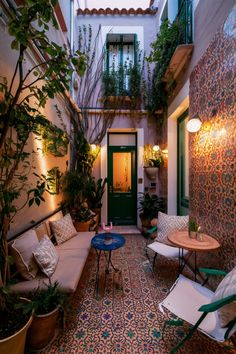 Cozy outdoor courtyard with patterned floor, potted plants, white cushioned seating, and a green door. Simple Small Patio Ideas, Small Courtyard Patio, Small Outdoor Patio Ideas Townhouse, Small Townhouse Backyard Ideas, Townhouse Courtyard, Yard Upgrades, Patio Garden Ideas On A Budget, Apartment Backyard, Veranda Ideas