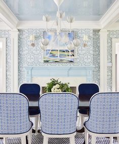 a dining room with blue chairs and a table in front of a fire place on the wall