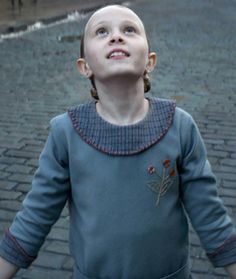 a young boy standing on top of a brick road