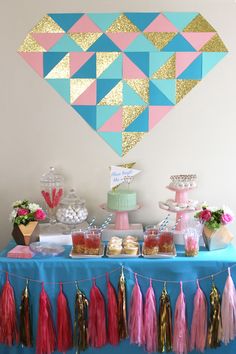 a table topped with cake and tassels covered in pink, blue and gold