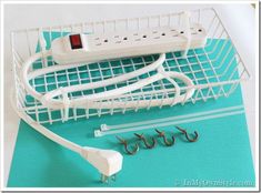 a white wire basket with several hooks and wires in front of it on top of a blue surface