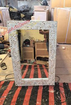 a mirror sitting on top of a striped rug next to boxes and other items in a room