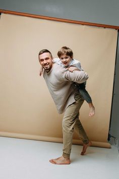 a man holding a young boy in his arms while posing for a photo with a backdrop behind him