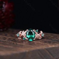 an emerald colored ring with leaves on the side and two green stones in the middle