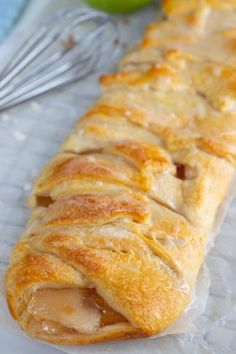 an apple pie is sitting on wax paper next to a fork and green apple in the background