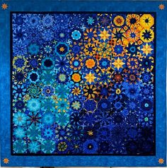 a blue and yellow quilt with many different designs on the front, along with stars in the background