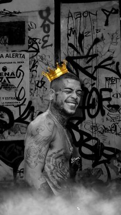 a man with a crown on top of his head in front of graffiti covered walls