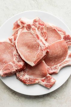 raw pork chops on a white plate