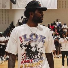 a man standing on top of a basketball court wearing a white shirt and black hat