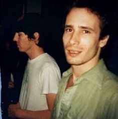 two young men standing next to each other in front of a man wearing a green shirt