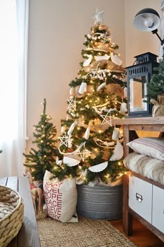 a decorated christmas tree in a living room next to a basket with ornaments on it