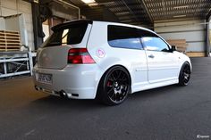 the back end of a white car parked in a garage