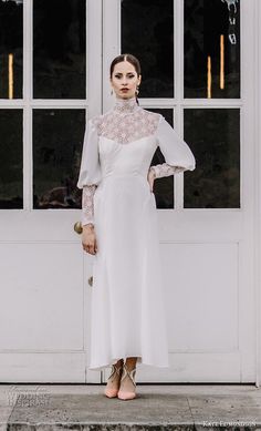 a woman standing in front of a door wearing a white dress with sheer neckline