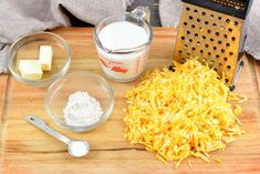 the ingredients for making cheese are displayed on a wooden cutting board with graters