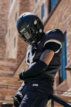 a football player wearing a uniform and holding his helmet on the side of a building