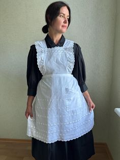 a woman standing in front of a wall wearing an apron