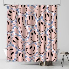 a pink shower curtain with black and white smiley faces on it, sitting next to a chair