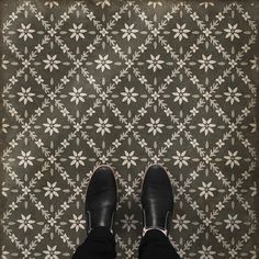 a person standing in front of a floral wallpaper with black and white flowers on it