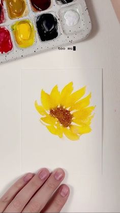 someone is painting a sunflower with watercolors