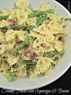 pasta with asparagus and bacon in a white bowl on a black tablecloth