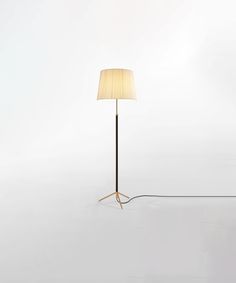 a floor lamp with a white shade on it and a black cord in the middle