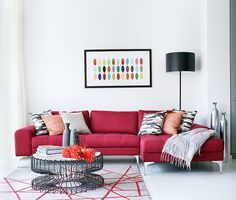 a living room with a red couch, coffee table and painting hanging on the wall