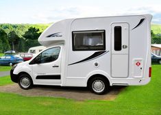 an rv parked in the grass near other cars