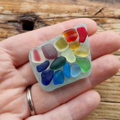 a hand holding a small multicolored sea glass piece in it's palm