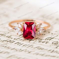 a ring with a red stone and three white stones on it, sitting on top of a