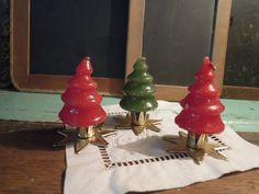 three small christmas trees sitting on top of a white napkin next to a window sill