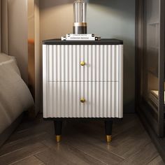 a white and black cabinet with gold handles in a room next to a lamp on a nightstand