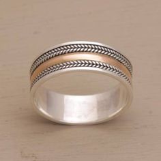 a silver and gold ring sitting on top of a wooden table