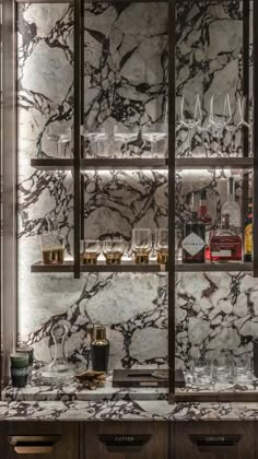 a marble bar with wine glasses and liquor bottles on the shelves in front of it