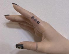 a woman's hand with a small flower tattoo on her left thumb and finger