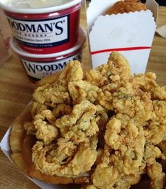 fried food sitting on top of a wooden table next to a container of yogurt