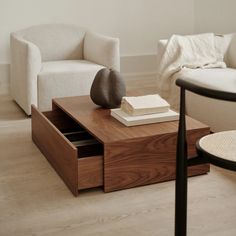 a living room with two white chairs and a coffee table in the middle, on top of a hard wood floor