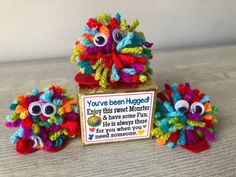 three colorful knitted pom poms sitting on top of a wooden table next to a sign that says you've been happy