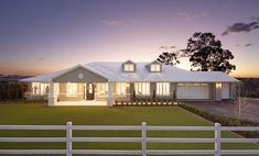 a white house sitting on top of a lush green field next to a white fence