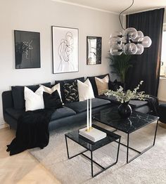 a living room filled with black furniture and white pillows on top of a rug next to a coffee table