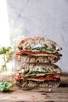 two sandwiches stacked on top of each other with lettuce and tomato in the middle