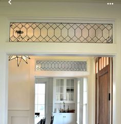 an open door leading to a kitchen and dining room area with white walls, wood flooring and stained glass windows