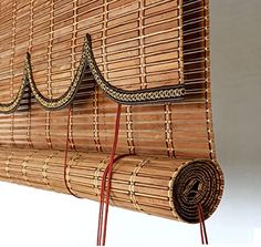 a bamboo wall hanging on the side of a white wall with red wires attached to it