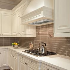 a kitchen with white cabinets and a stove top oven next to a bowl of fruit