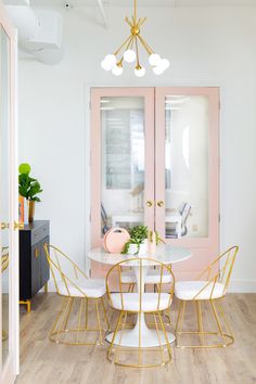 a dining room with pink doors and white chairs