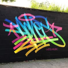 graffiti painted on the side of a black brick wall with colorful writing that says hope