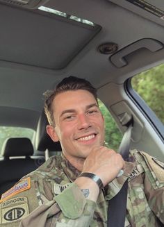 a man in uniform is sitting in the back seat of a car and smiling at the camera