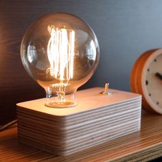 a light bulb sitting on top of a wooden block next to a small alarm clock